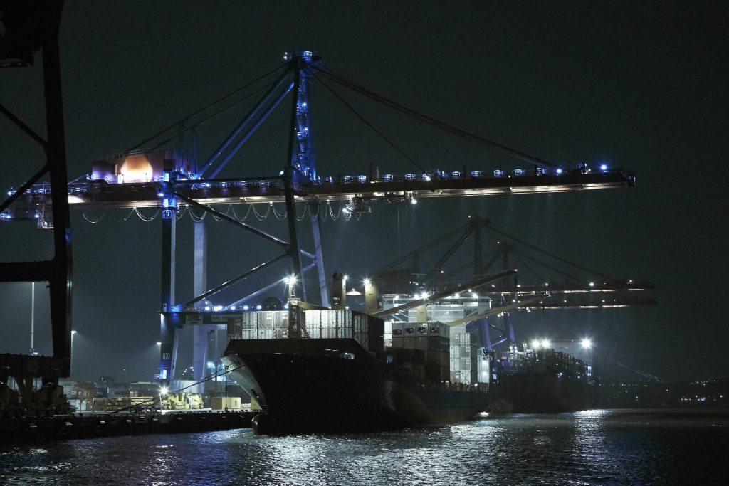 Containerfartyg somligger vid kaj och lastar under kran på natten