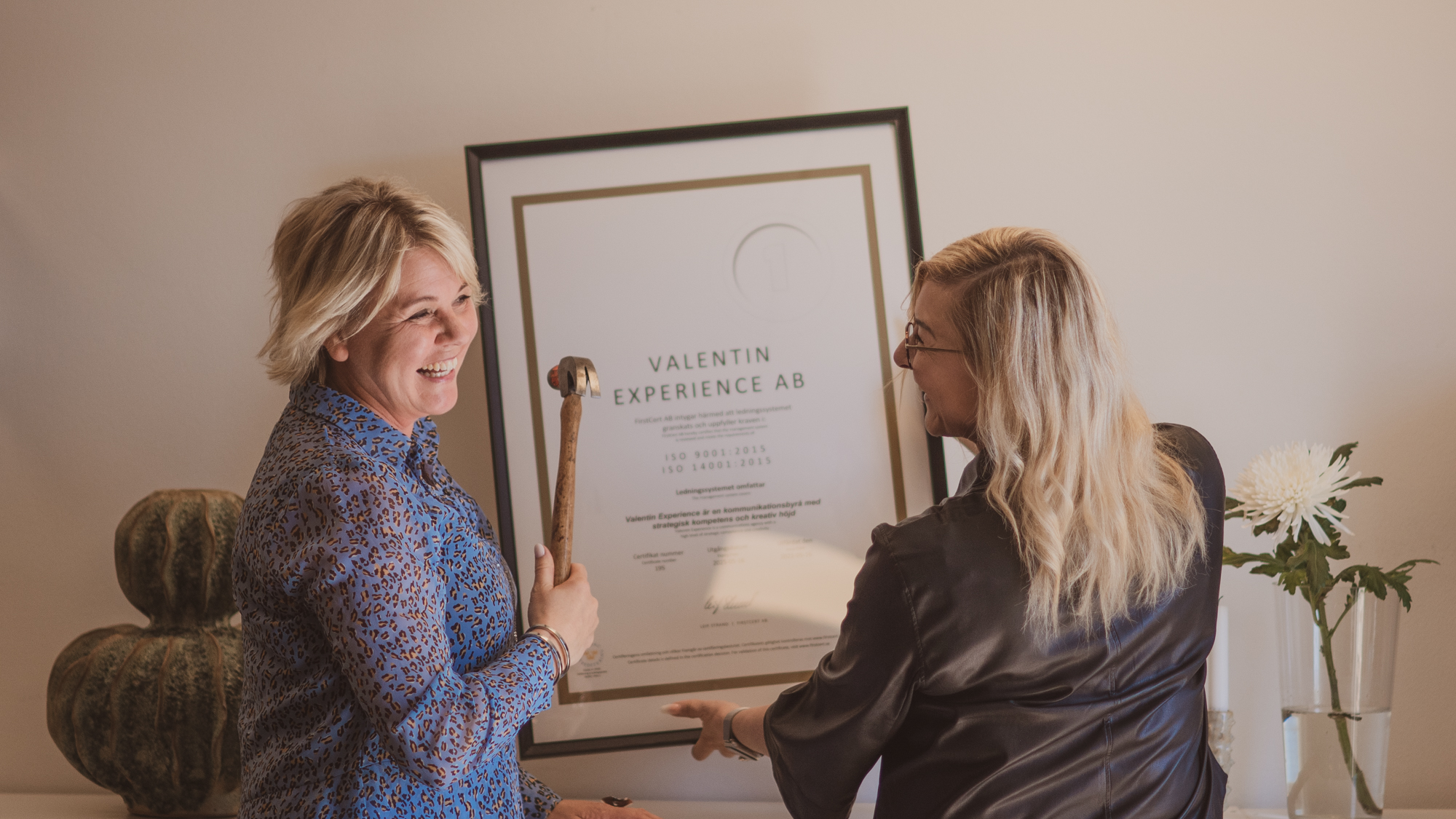 Personal på Valentin Experience kommunikationsbyrå hänger upp diplom för ISO-certifiering